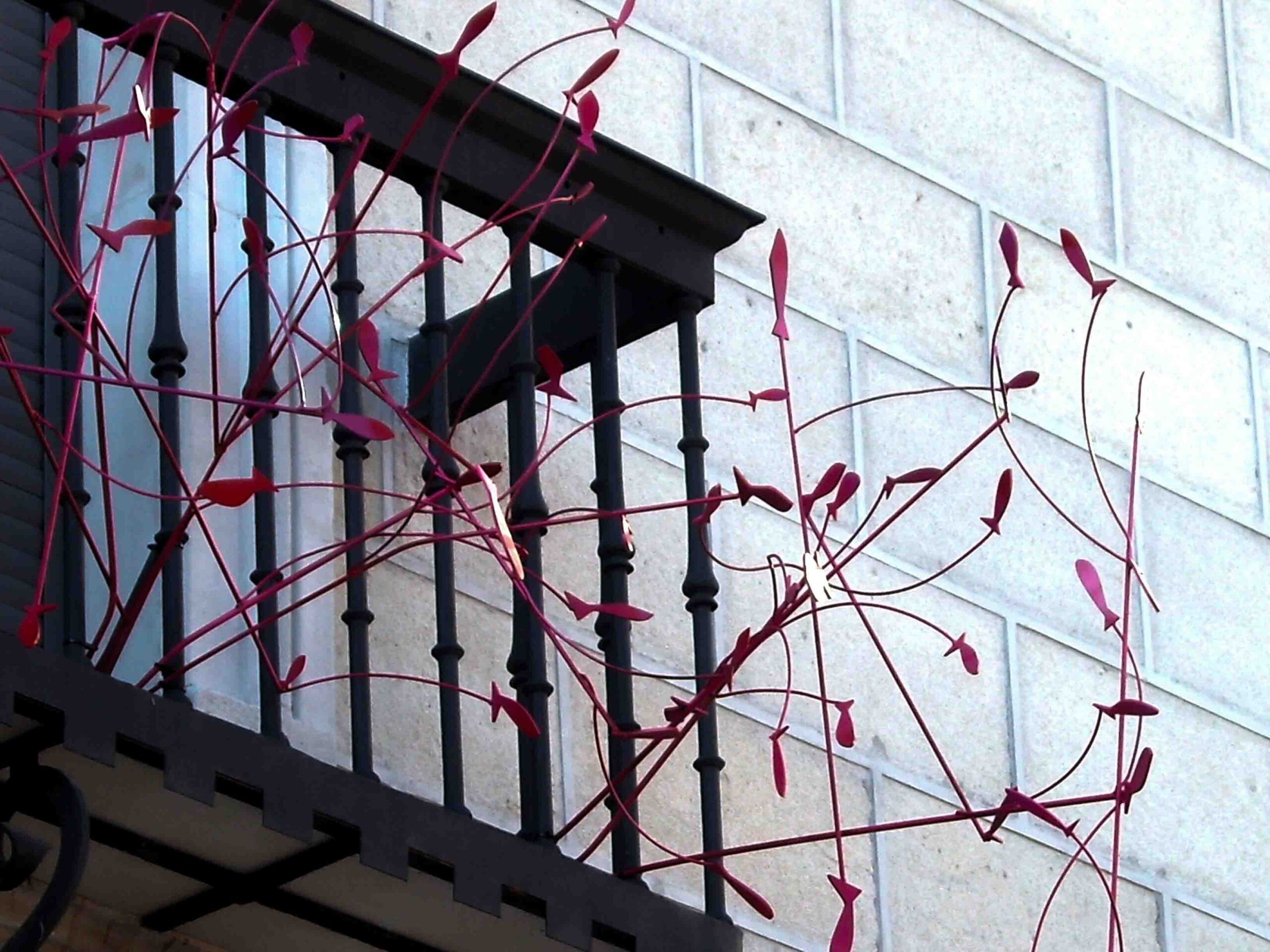 Barandilla de un balcón con ramificaciones de color rosa acabadas en peces, parte de la colección peces voladores