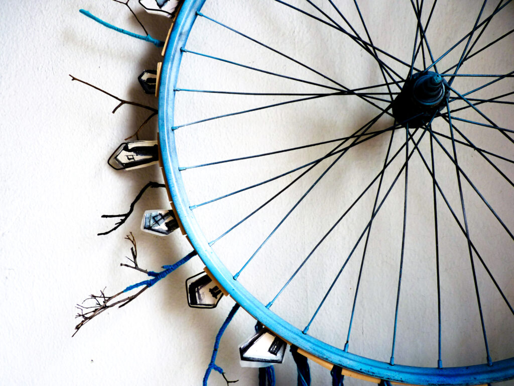 Rueda de bicicleta de color azul, la parte exterior está decorada con pequeñas figuras de casas u árboles alrededor de toda la rueda